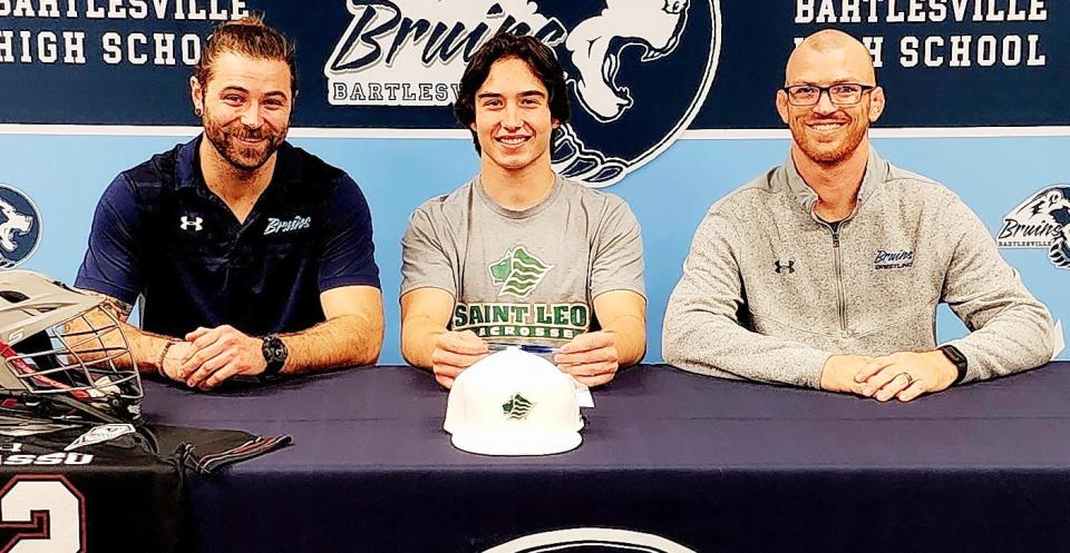 Bartlesville High student-athlete Duke McGill, center, is joined by strength coach Daniel West, left, and head wrestling coach Josh Pulsifer as McGill signs a letter of intent to play lacrosse for St. Leo (Fla.) University.