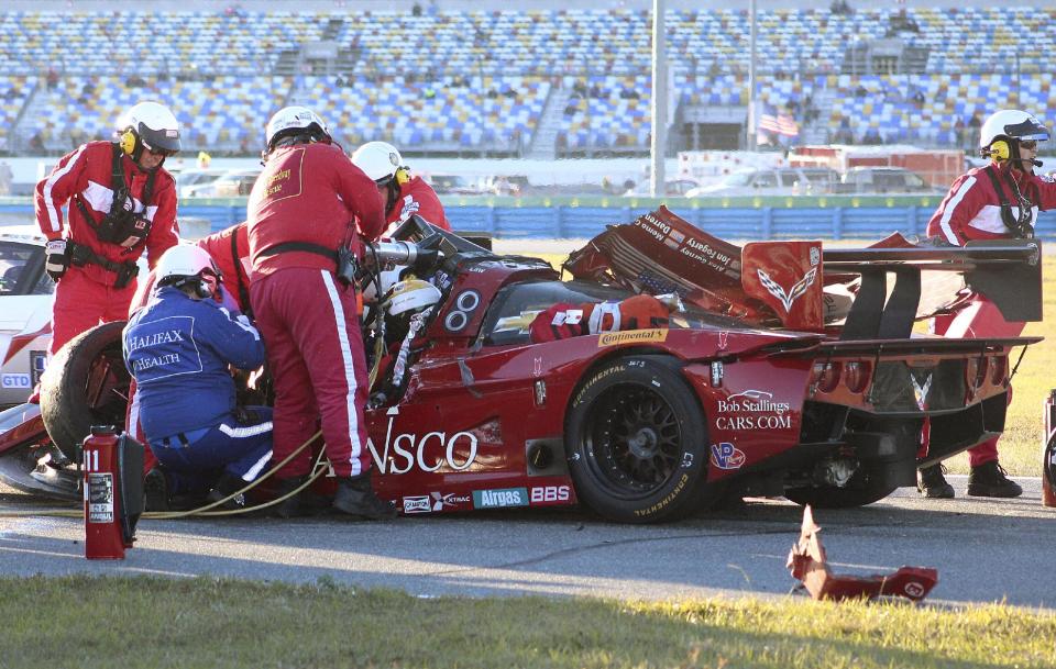 Rescue workers remove driver Memo Gidley from his car after he was involved in a crash during the IMSA Series Rolex 24 hour sports car race at Daytona International Speedway in Daytona Beach, Fla., Saturday, Jan. 25, 2014. (AP Photo/Dow Graham)