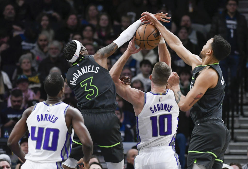 Sacramento Kings center Domantas Sabonis (10) vies for rebound with Minnesota Timberwolves forwards Jaden McDaniels (3) and Kyle Anderson, right, as Kings forward Harrison Barnes (40) watches during the first half of an NBA basketball game Saturday, Jan. 28, 2023, in Minneapolis. The Timberwolves won 117-110. (AP Photo/Craig Lassig)