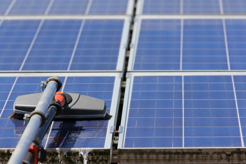 tool washing solar panels on residential roof