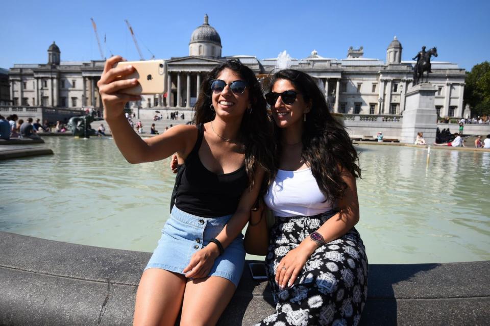 Two women take a selfie during a hot day in Trafalgar Square (PA)