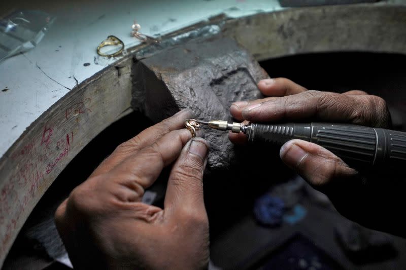 An employee fills a ring at a diamond jewellery manufacturing factory in Mumbai