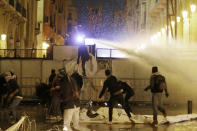 Anti-government protesters are sprayed by a water cannon as they clash with the riot police during ongoing protests in Beirut, Lebanon, Wednesday, Jan. 22, 2020. Lebanon's new government held its first meeting Wednesday, a day after it was formed following a three-month political vacuum, with the prime minister saying his Cabinet will adopt financial and economic methods different than those of previous governments. (AP Photo/Bilal Hussein)