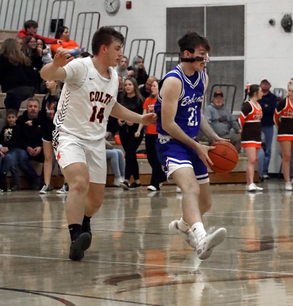 Cambridge's Rylan Mathews (21) dribbles the ball with Meadowbrook senior Zayden Yeagle (14) during the Colts versus Bobcats basketball game Tuesday evening at Meadowbrook High School. Yeagle, who finished with a pair of steals was recognized as the Colts' lone senior in a brief ceremony prior to the game