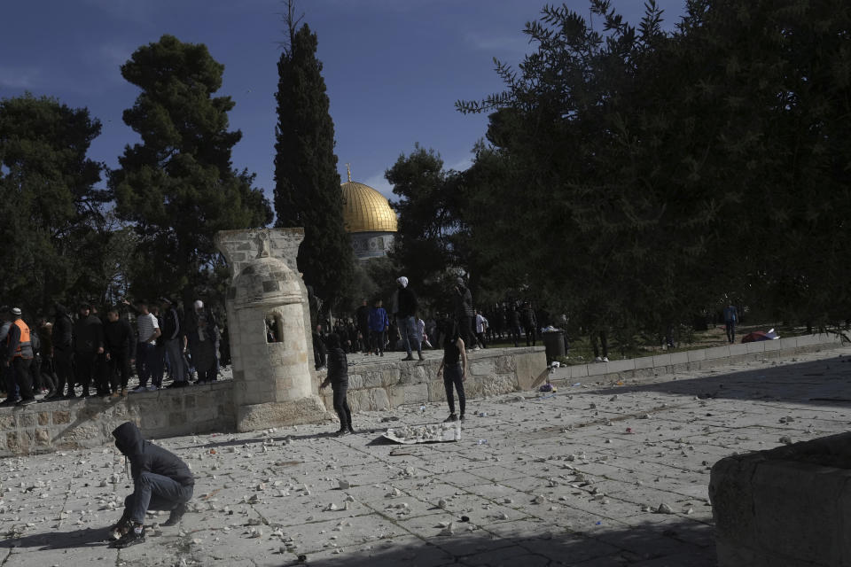 Palestinians gather stones to throw at Israeli police after they entered the Al Aqsa Mosque compound, in Jerusalem's Old City, Friday, April 22, 2022. (AP Photo/Mahmoud Illean)