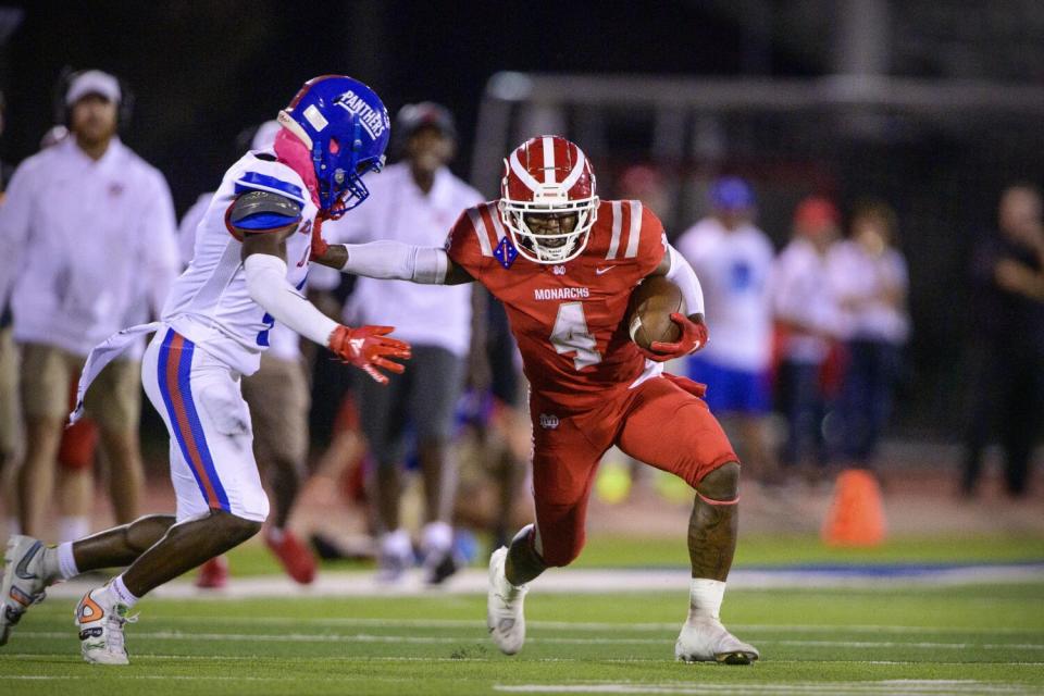 Mater Dei Monarchs running back Raleek Brown stiff arms a defender while running for a first down.