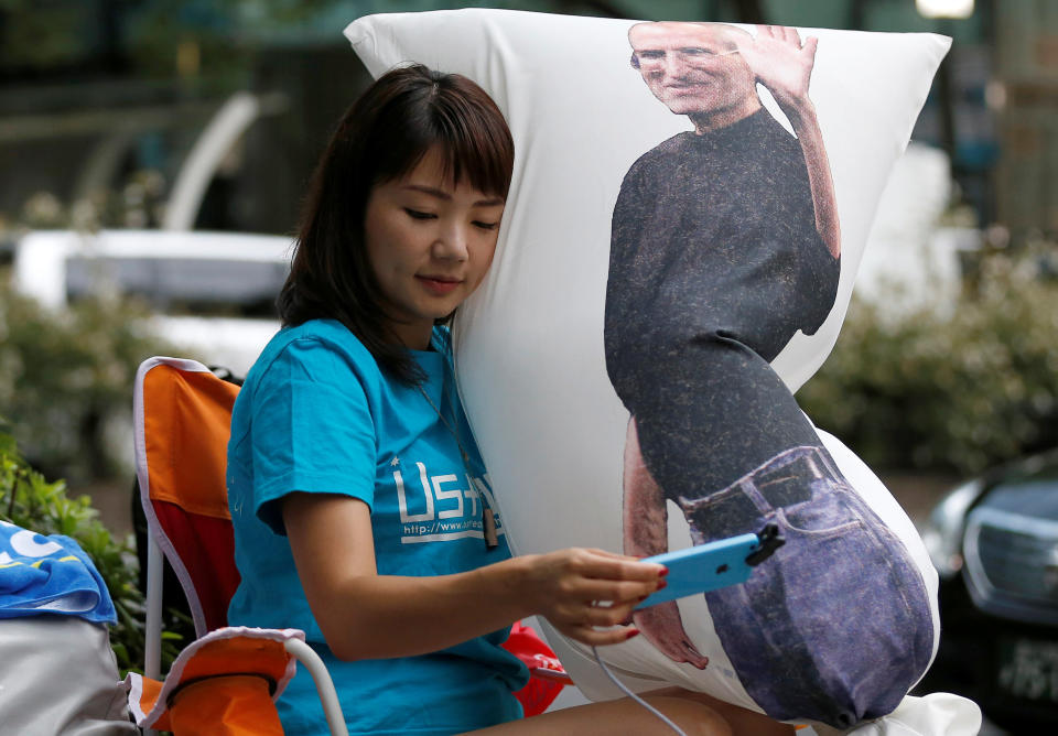 Ayano Tominaga holds a cushion printed a portrait of Apple co-founder Steve Jobs on it, as she sits in queue for the release of Apple's new iPhone 7 and 7 Plus in front of the Apple Store in Tokyo's Omotesando shopping district, Japan, September 16, 2016. REUTERS/Issei Kato