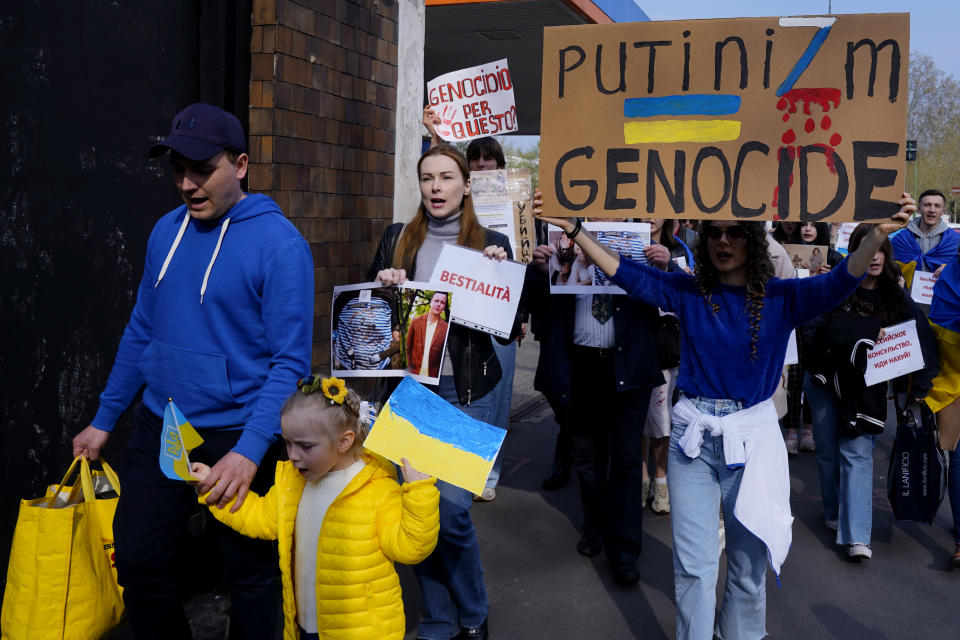 Demonstrators in Italy hold posters saying Bestiality in Italian, and Putinizm Genocide.