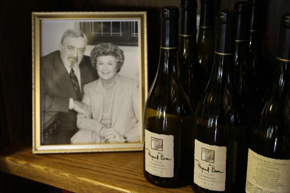 In this photo taken Thursday, April 11, 2013 bottles of Chardonnay are shown beside of photograph of the late actor Raymond Burr and actress Barbara Hale at Raymond Burr Vineyards in Healdsburg Calif. The star of TV’s “Perry Mason” and “Ironside,” also had a passion for wine, which is still celebrated at this small winery in Sonoma County’s Dry Creek Valley. (AP Photo/Eric Risberg)