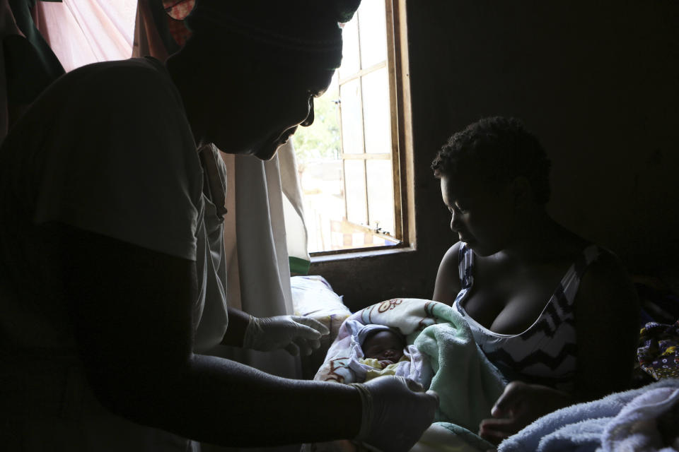 72-year old grandmother Esther Zinyoro Gwena, left, attends to 18-year old Perseverance Kanyoza, after helping to deliver her baby in her tiny apartment in the poor surburb of Mbare in Harare, Zimbabwe in this Saturday, Nov. 16, 2019. Grandmother Esther Zinyoro Gwena claims to be guided by the holy spirit and has become a local hero, as the country’s economic crisis forces closure of medical facilities, and mothers-to-be seek out untrained birth attendants. (AP Photo/Tsvangirayi Mukwazhi)