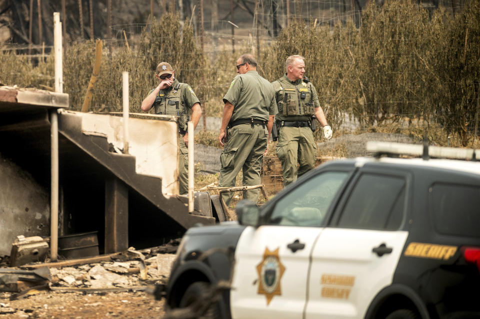 Sheriff's deputies search a scorched residence following the McKinney Fire on Tuesday, Aug. 2, 2022, in Klamath National Forest, Calif. Their team did not find any fire victims at the property. (AP Photo/Noah Berger)