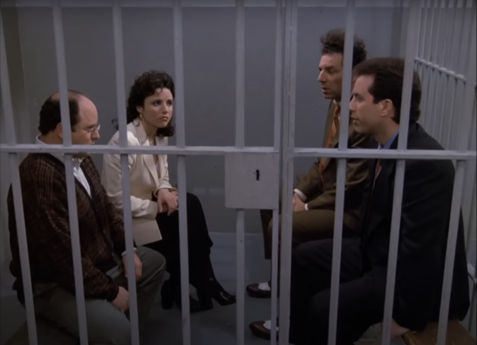 Four characters from 'Seinfeld' sit in a jail cell, with expressions ranging from concerned to indifferent