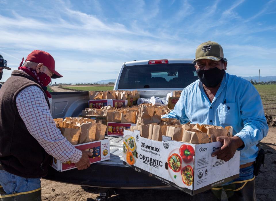 Miguel Alcalá, a la izquierda, y su colega Emilio Velasco llevan cajas llenas de almuerzos donados por los propietarios de negocios locales para distribuirlos a los trabajadores agrícolas en Salinas, Calif., el 16 de mayo. Cada bolsa de comida contiene un sándwich de carne deshebrada, papas fritas y agua embotellada.