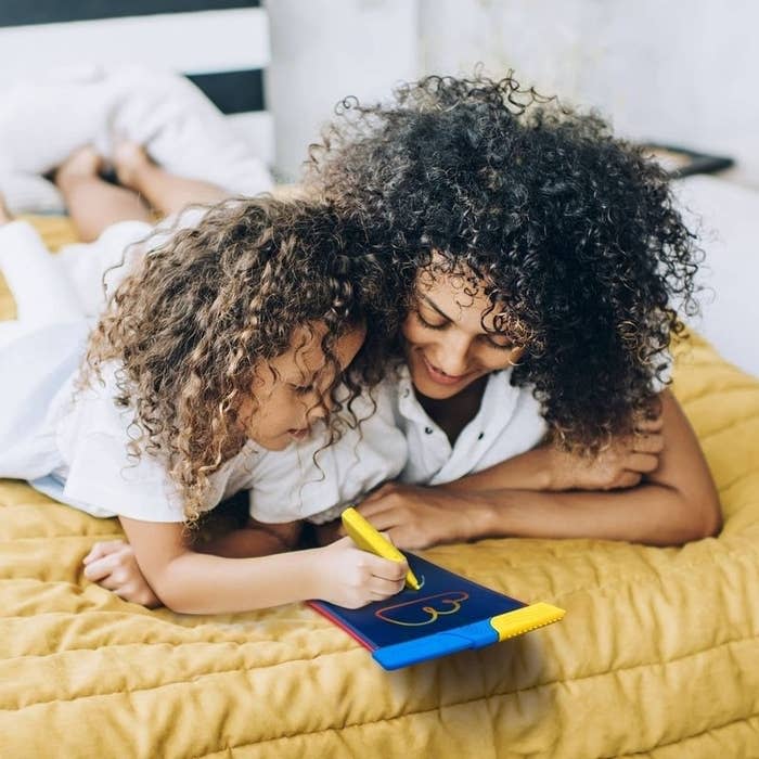 A child and adult play with a doodle pad