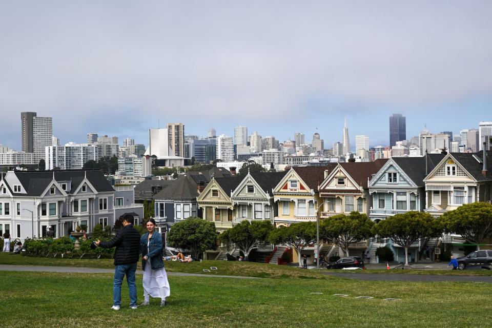 People spend time in front of the famous Victorian houses called 'Painted Ladies' at Alamo Square in San Francisco, California, United States on August 9, 2023.