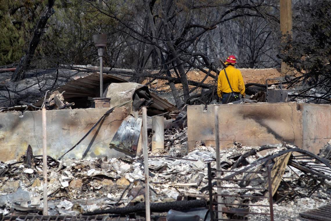 A firefighter observes the wreckage after a structure collapsed because of a wildfire on the shore of Possum Kingdom Lake in Graford, Texas, on Wednesday, July 20, 2022.