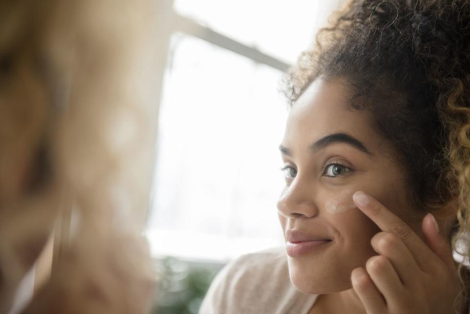 woman applying lotion to cheek