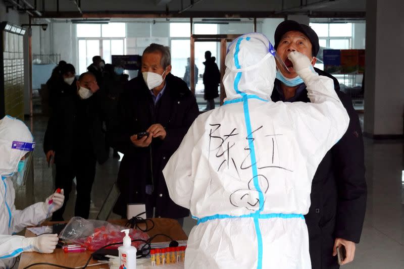 Medical worker collects a swab sample from a man for nucleic acid testing in Xian