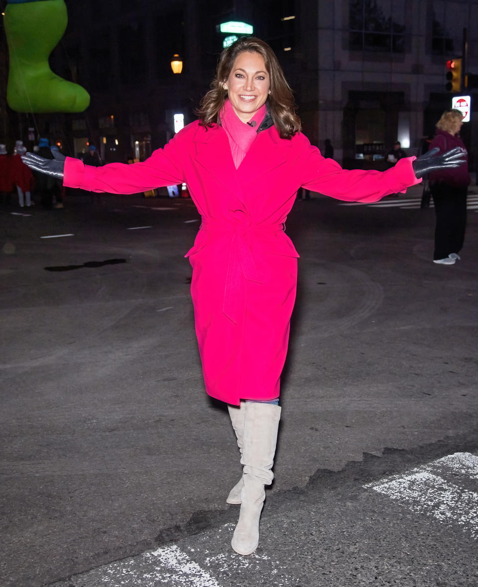 Ginger Zee stands with her arms open in a pink coat