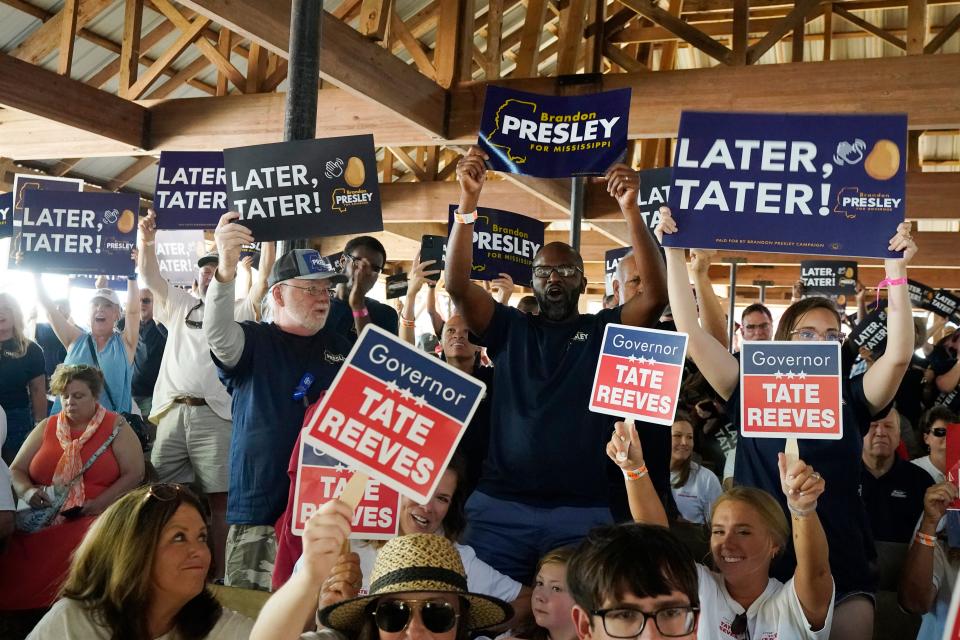 Contrasting groups of supporters for the incumbent Mississippi Gov. Tate Reeves and Democrat Brandon Presley wave their respective candidates' signs at the Neshoba County Fair in Philadelphia, Miss., Thursday, July 27, 2023. (AP Photo/Rogelio V. Solis)