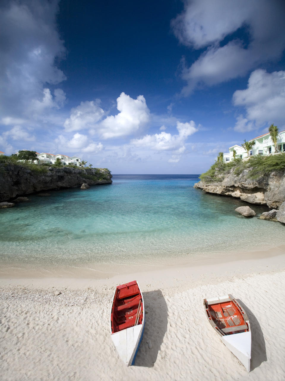 Two fishing boats pulled up on a white sand beach.