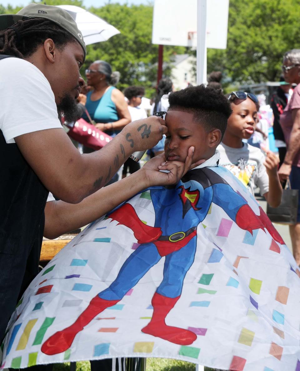 Antonio Goodwin Jr., 8, of Akron, gets his hair cut by Levander Anderson of Legends Barbershop & Lounge, who provided free haircuts during the festival.