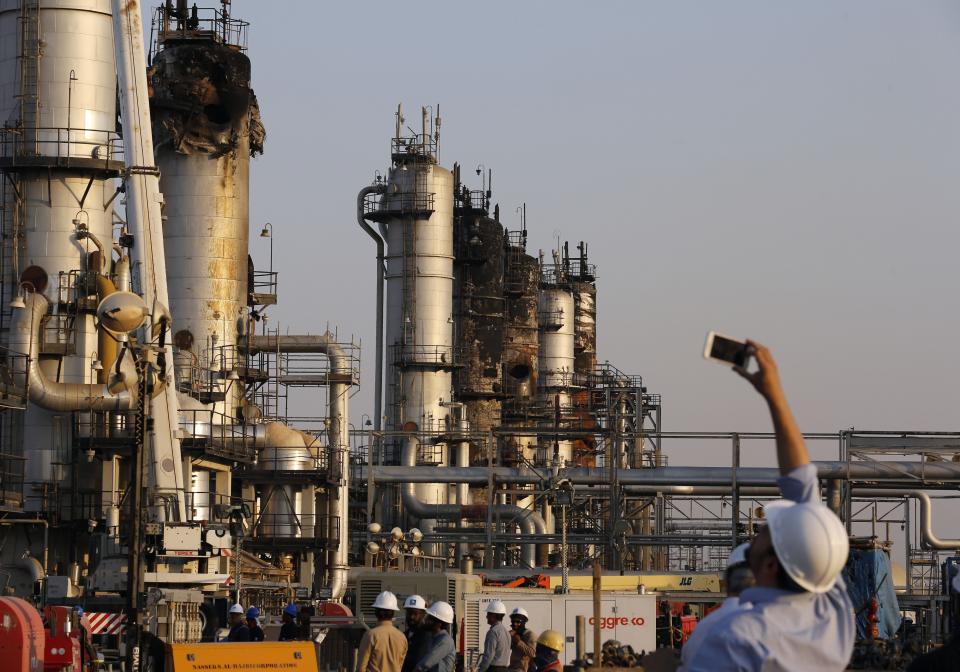 FILE- In this Friday, Sept. 20, 2019, file photo, during a trip organized by Saudi information ministry, a cameraman films Aramco's oil processing facility after the recent Sept. 14 attack in Abqaiq, near Dammam in the Kingdom's Eastern Province. Saudi Arabian oil company Aramco's initial public offering raised $29.4 billion, more than previously announced after the company said Sunday it used a so-called "greenshoe option" to sell an additional 450 million shares to satiate investor demand. (AP Photo/Amr Nabil, File)