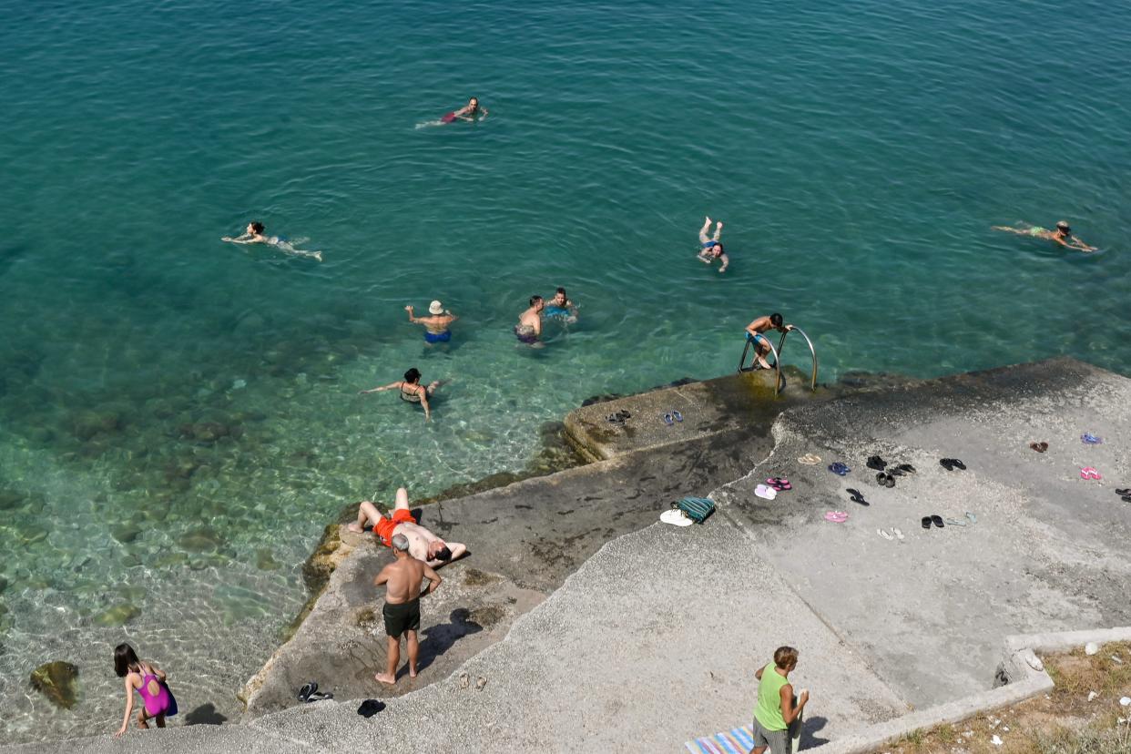 Locals and tourists cool off at a beach in the touristic town of Nafplion in Greece (AFP via Getty Images)
