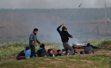 Palestinian demonstrators take cover as others hurl stones at Israeli troops during a protest at the Israel-Gaza border fence, east of Gaza City February 22, 2019. REUTERS/Mohammed Salem