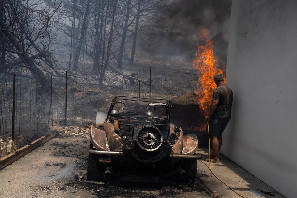 A resident tries to extinguish the flames at the yard of a house on the Aegean Sea island of Rhodes, southeastern Greece on Monday.