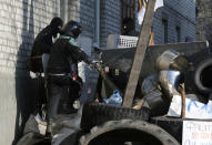 Pro-Russian protesters guarding a barricade, give way to their comrade, in Slovyansk , eastern Ukraine, Wednesday, April 16, 2014. The city of Slovyansk has come under the increasing control of the pro-Russian gunmen who seized it last weekend. (AP Photo/Sergei Grits)