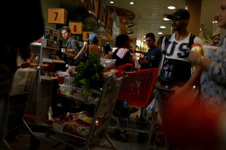 A man waits in line to pay for food at the cashier of a supermarket in Caracas, Venezuela March 10, 2017. REUTERS/Carlos Garcia Rawlins