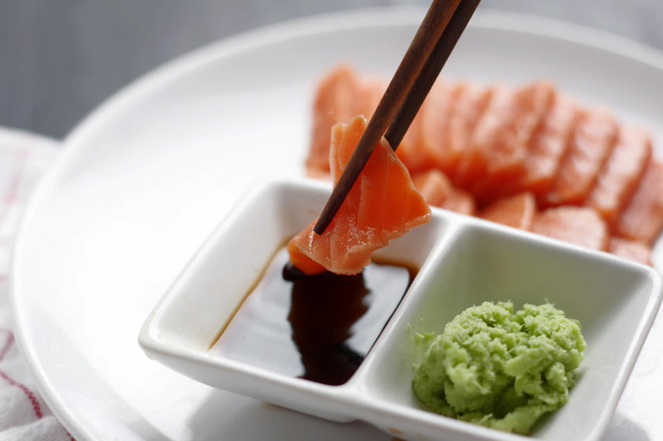 Someone dipping sushi in soy sauce