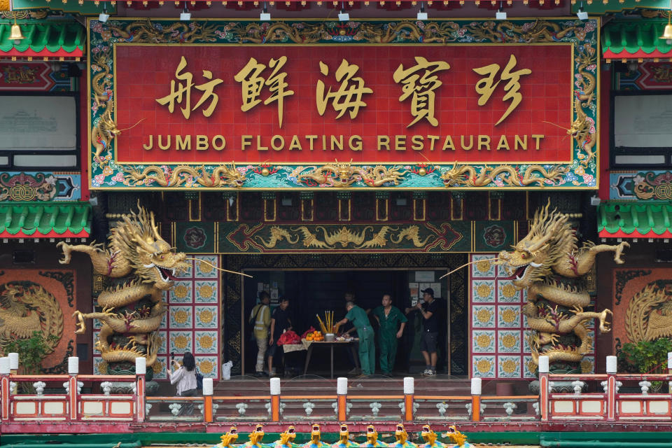 Staff members worship god on board of the Hong Kong's iconic Jumbo Floating Restaurant in Hong Kong, Tuesday, June 14, 2022. Hong Kong's iconic restaurant on Tuesday departed the city, after its parent company failed to find a new owner and lacked funds to maintain the establishment amid months of COVID-19 restrictions. (AP Photo/Kin Cheung)