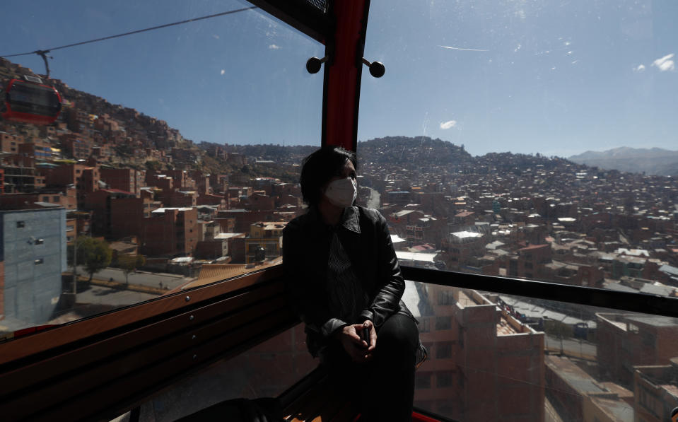 Una mujer con una mascarilla para protegerse del contagio del nuevo coronavirus viaja en un teleférico que conecta la ciudad de La Paz con El Alto, Bolivia, el domingo 31 de mayo de 2020. (Foto AP/Juan Karita)