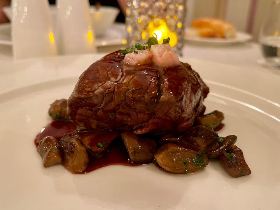 Plate of steak topped with garnish.