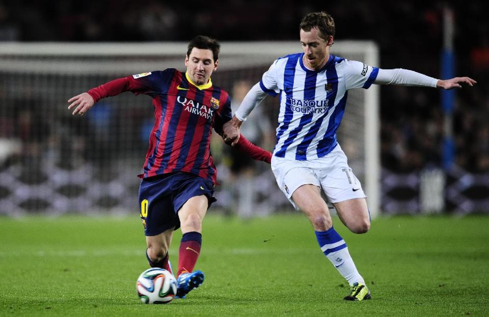 FC Barcelona's Lionel Messi, left, duels for the ball against Real Sociedad's Carlos Vela during a Copa del Rey soccer match at the Camp Nou stadium in Barcelona, Spain, Wednesday, Feb. 5, 2014. (AP Photo/Manu Fernandez)