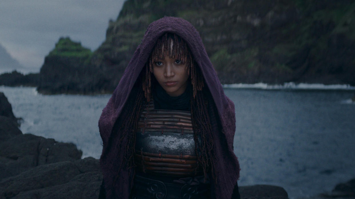  A hooded Mae stands on a shoreline in Star Wars: The Acolyte. 