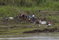 A family of illegal gold miners shouts from the shore after their dredging barge was set in fire by officers of the Brazilian Institute of the Environment and Renewable Natural Resources, IBAMA, during an operation to try to contain illegal gold mining on the Madeira river, a tributary of the Amazon river in Borba, Amazonas state, Brazil, Sunday, Nov. 28, 2021. Hundreds of barges belonging to illegal miners had converged on the river during a gold rush in the Brazilian Amazon prompting IBAMA authorities to start burning them. (AP Photo/Edmar Barros)