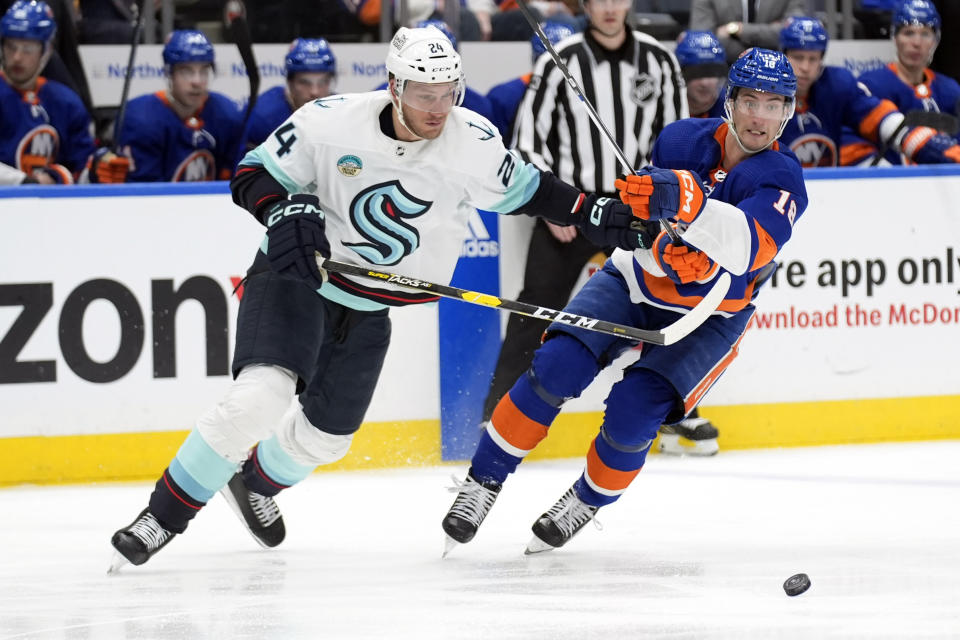 Seattle Kraken's Jamie Oleksiak, left, and New York Islanders' Pierre Engvall go for the puck during the second period of an NHL hockey game, Tuesday, Feb. 13, 2024, in Elmont, N.Y. (AP Photo/Seth Wenig)