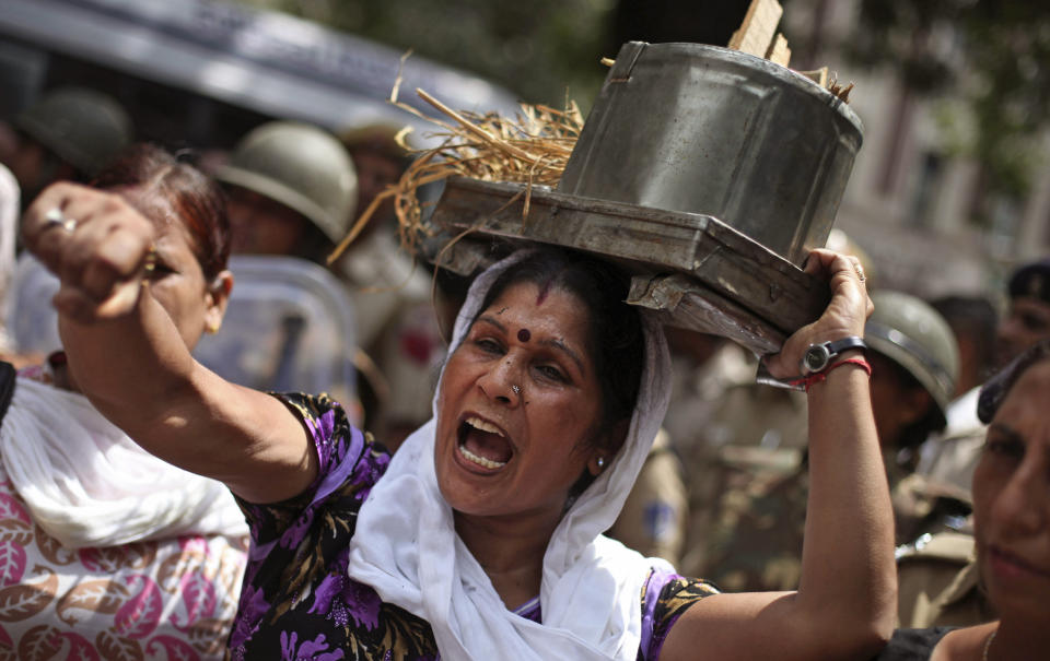 An activist of India’s main opposition Bharatiya Janata Party (BJP) shouts slogans as she carries an old cooking stove on her head during a protest in New Delhi, India, Saturday, Sept. 15, 2012. India's beleaguered government faced angry protests from its political allies as well as the opposition after it raised the price of diesel fuel in a bid to curb a ballooning national deficit and also announced a reduction in cooking gas subsidies. (AP Photo/Altaf Qadri)