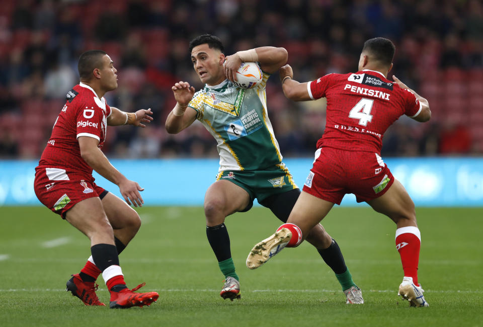 Cook Islands' Kayal Iro, centre, is tackled by Tonga's Will Penisini, right, during the Rugby League World Cup group D match against Tongo at the Riverside Stadium in Middlesbrough, England, Sunday Oct. 30, 2022. (Will Matthews/PA via AP)