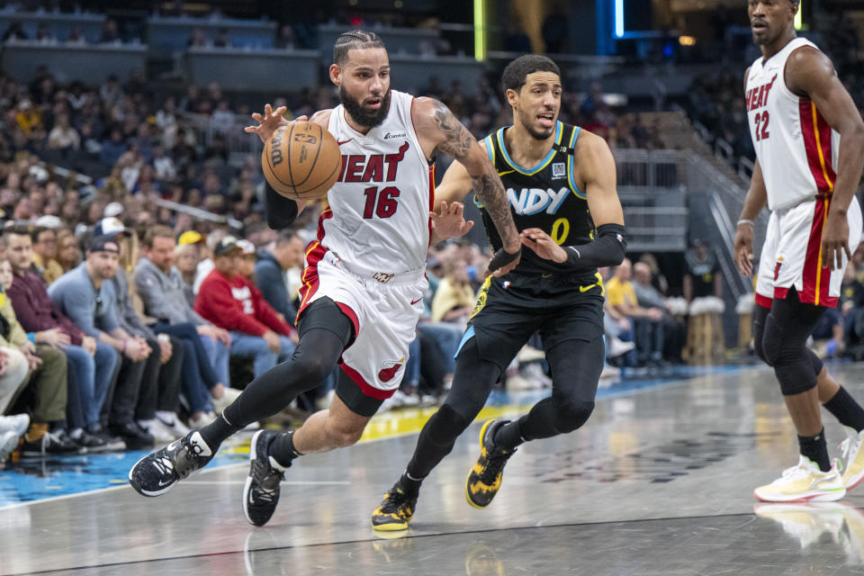 Miami Heat forward Caleb Martin (16) drives the ball past the defense of Indiana Pacers guard Tyrese Haliburton (0) during the first half of an NBA basketball game in Indianapolis, Sunday, April 7, 2024. (AP Photo/Doug McSchooler)