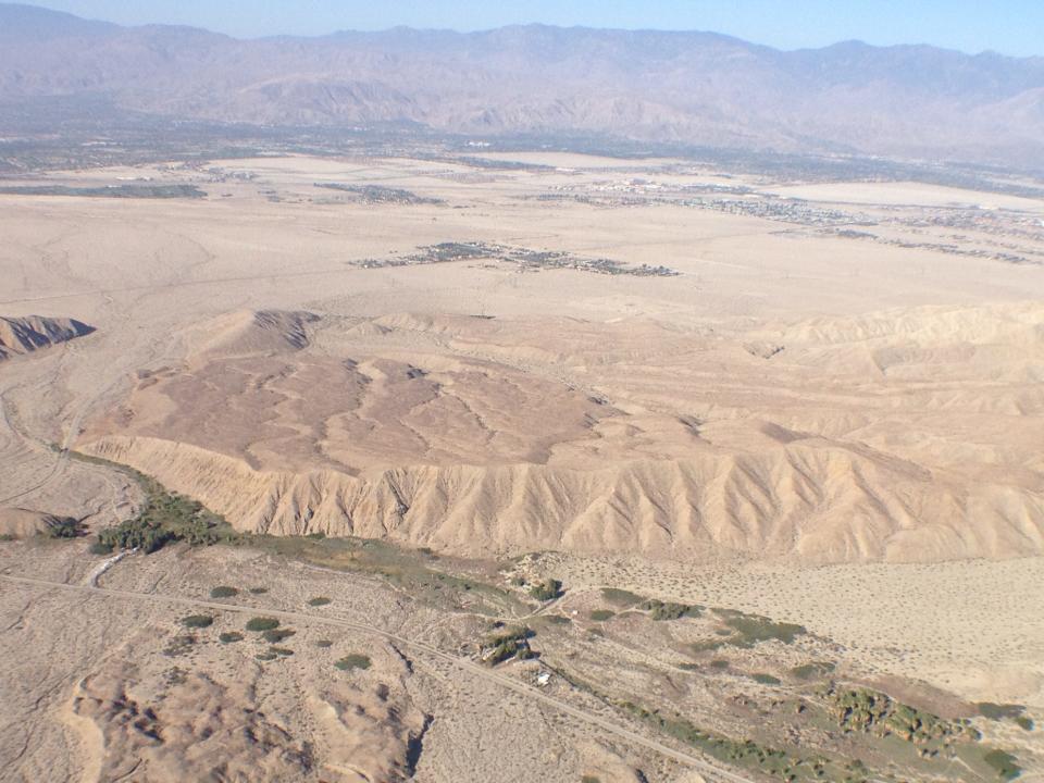 A hilly area where the San Andreas Fault runs through the Coachella Valley is seen from the air. An oasis of palm trees is sustained by water that gushes up along the fault line at the Coachella Valley Preserve.