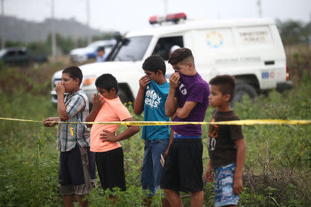 Children cover their noses near the body of a man who was killed in San Pedro Sula, Honduras, June 4, 2018. REUTERS/Edgard Garrido