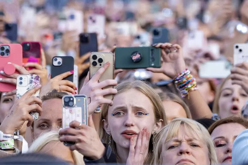 Taylor Swift fans holding up their phones to record the star