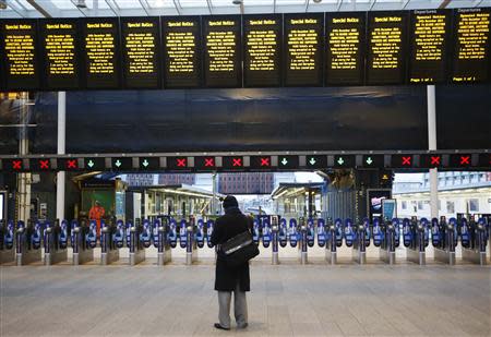 A man stands alone at London Bridge Station after numerous trains were cancelled due to storms in London December 24, 2013. REUTERS/Luke MacGregor