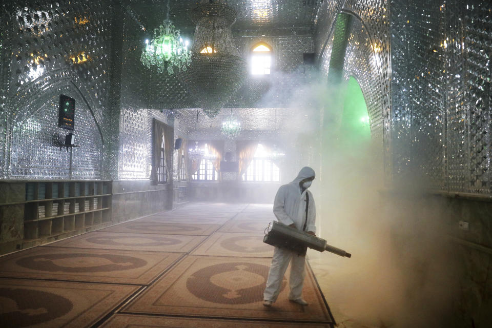 FILE - In this March, 6, 2020, file photo, a firefighter disinfects the shrine of Saint Saleh to help prevent the spread of the new coronavirus in northern Tehran, Iran. As cases of the coronavirus surge in Italy, Iran, South Korea, the U.S. and elsewhere, many scientists say it's plain that the world is in the grips of a pandemic — a serious global outbreak. (AP Photo/Ebrahim Noroozi, File)