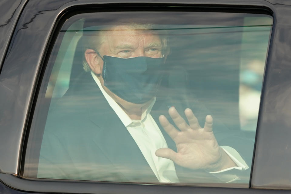 President Trump wears a face mask and waves from inside a vehicle