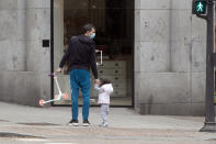 A man takes a young girl for a walk in Madrid, Spain, Sunday, April 26, 2020. On Sunday, children under 14 years old are allowed to take walks with a parent for up to one hour and within one kilometer from home, ending six weeks of compete seclusion due to the coronavirus outbreak. (AP Photo/Paul White)